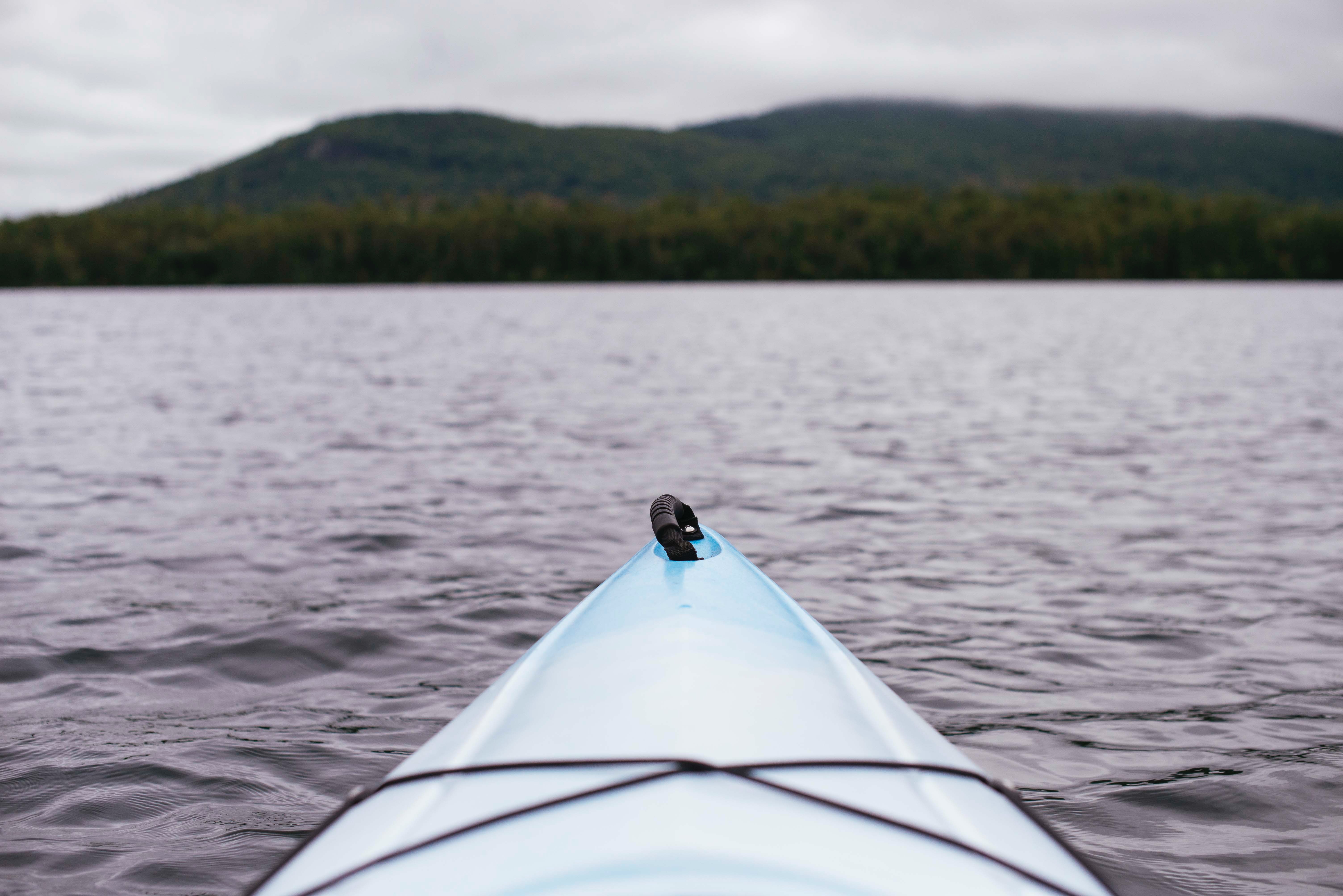 tip of a kayak on a lake with mountain in the backgrond