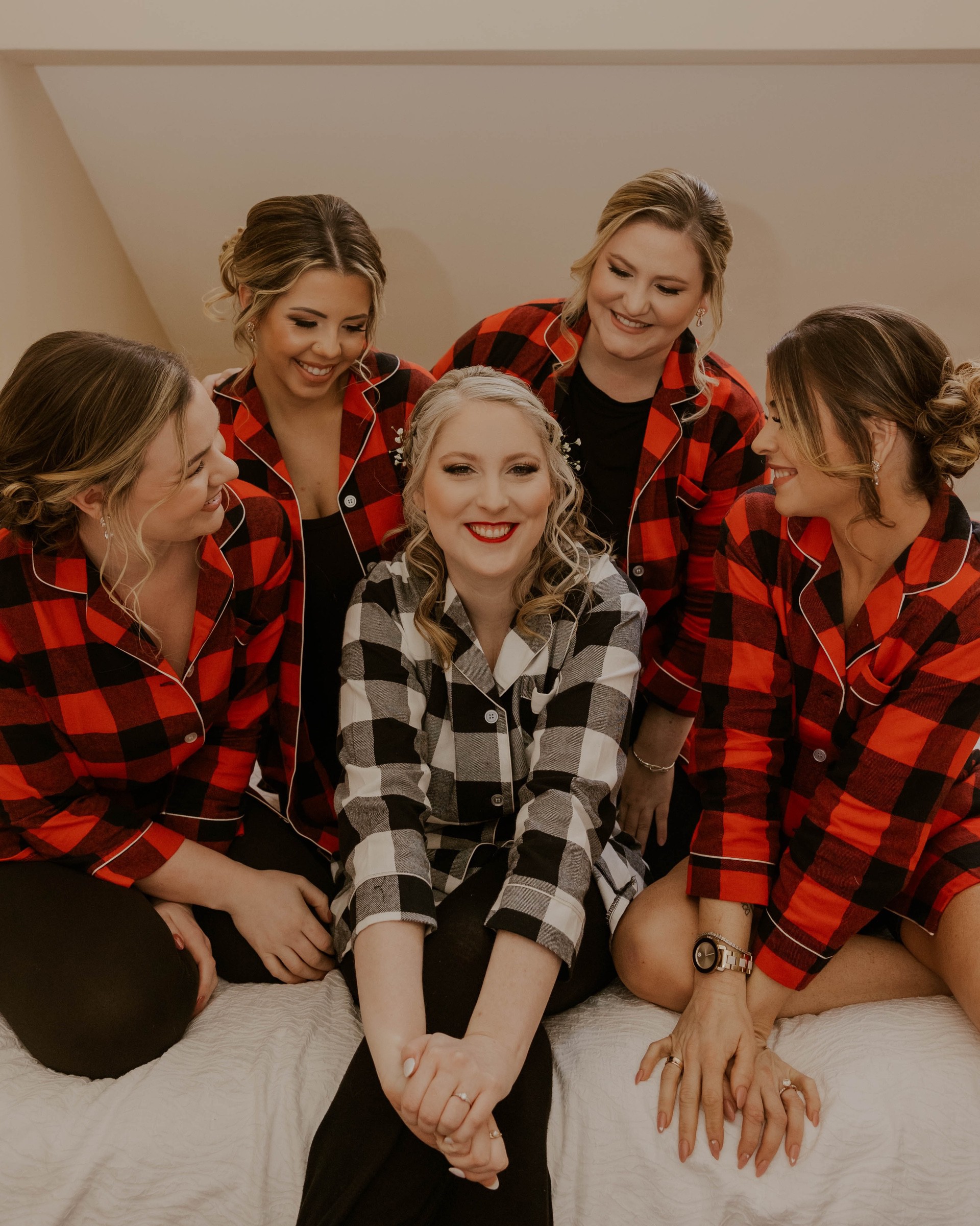 4 women in red buffalo plaid shirts sitting around a woman in a black and white buffalo plaid shirt
